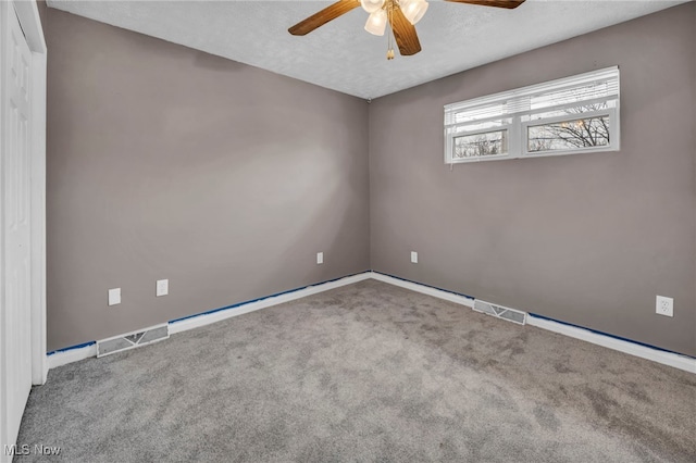 spare room with ceiling fan, a textured ceiling, carpet flooring, and visible vents