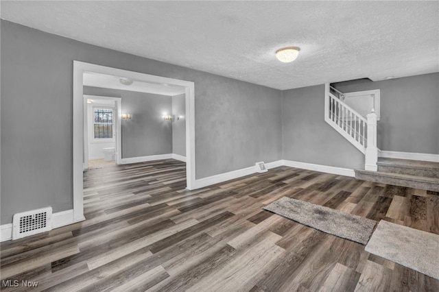 interior space with baseboards, visible vents, stairway, wood finished floors, and a textured ceiling