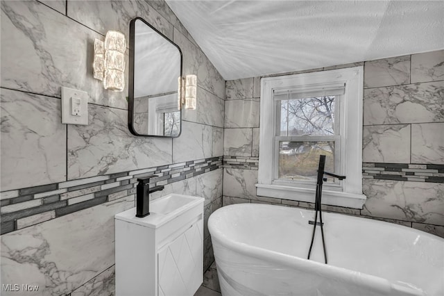 full bathroom with a freestanding bath, a textured ceiling, and vanity