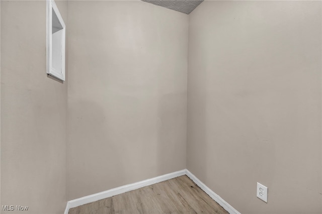 empty room with baseboards, a textured ceiling, and light wood-style floors