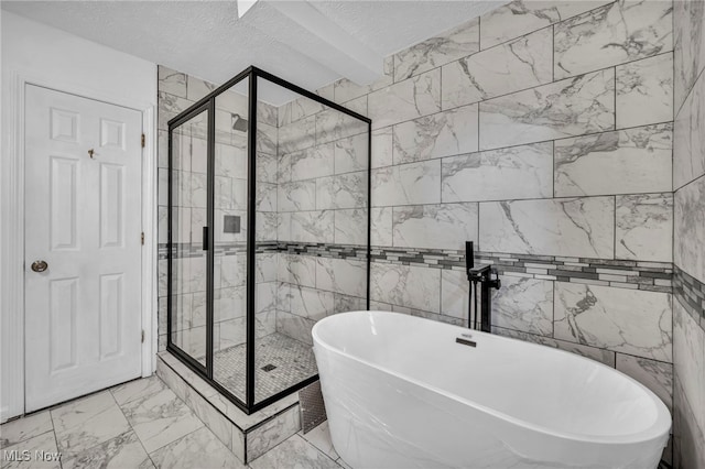 full bath featuring a textured ceiling, marble finish floor, a freestanding tub, and a shower stall