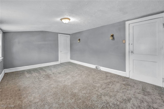 empty room with carpet floors, visible vents, baseboards, and a textured ceiling