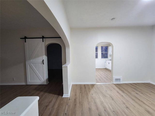 interior space with arched walkways, visible vents, baseboards, and wood finished floors