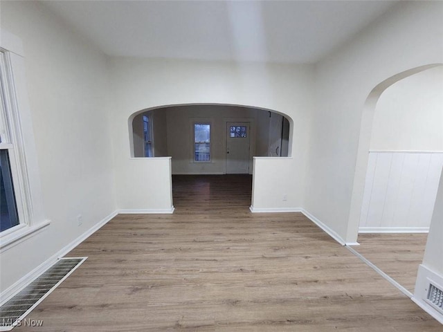 spare room featuring visible vents, arched walkways, and wood finished floors