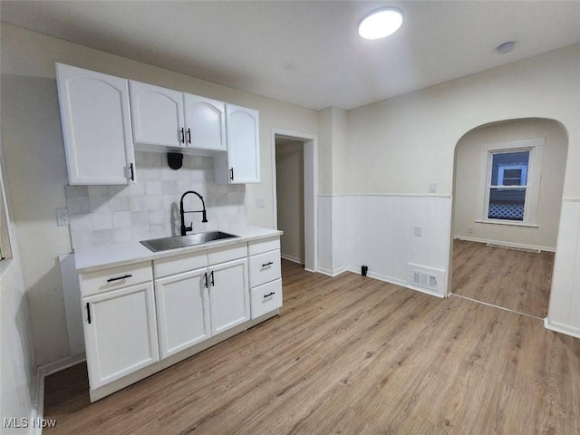 kitchen featuring visible vents, a sink, light wood finished floors, and white cabinetry