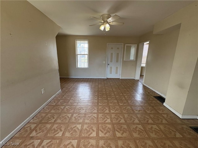 foyer entrance with a ceiling fan and baseboards