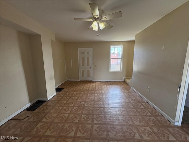 empty room with ceiling fan, visible vents, and baseboards