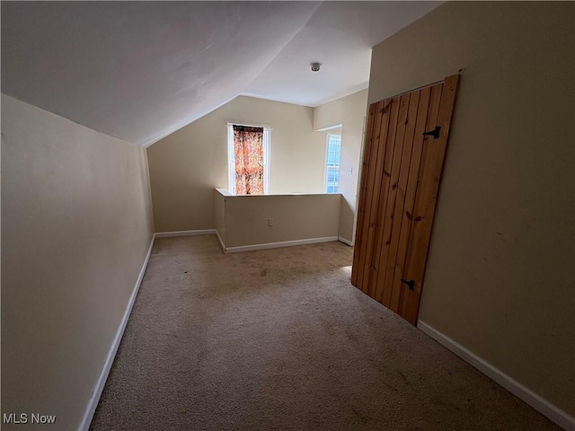 bonus room featuring lofted ceiling, carpet flooring, and baseboards