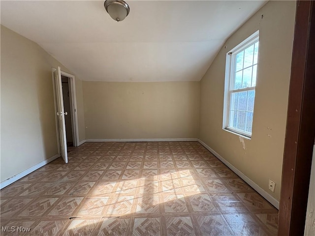 bonus room with lofted ceiling and baseboards