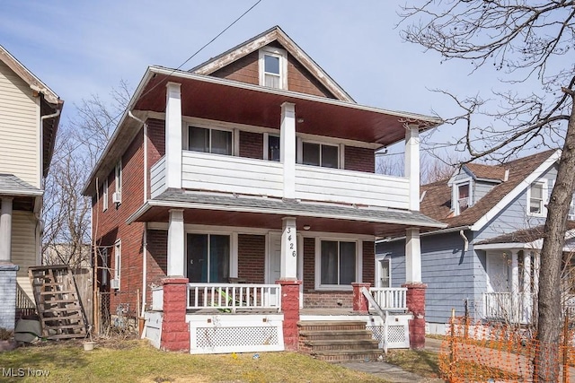 view of front of home with covered porch, brick siding, stairway, and a balcony