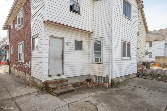 view of exterior entry with fence and a patio