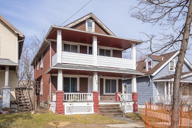 view of front of property with covered porch, brick siding, stairway, and a balcony