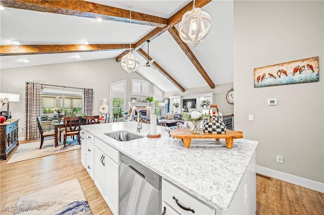 kitchen with open floor plan, beamed ceiling, a kitchen island with sink, stainless steel dishwasher, and a sink