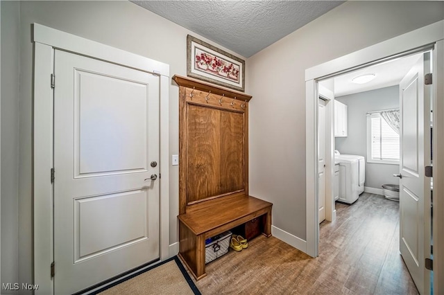 mudroom with a textured ceiling, baseboards, wood finished floors, and independent washer and dryer