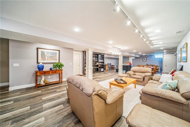 living area with rail lighting, visible vents, baseboards, and wood finished floors