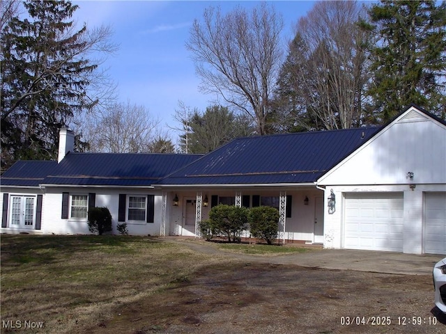 ranch-style home featuring metal roof, an attached garage, driveway, french doors, and a chimney