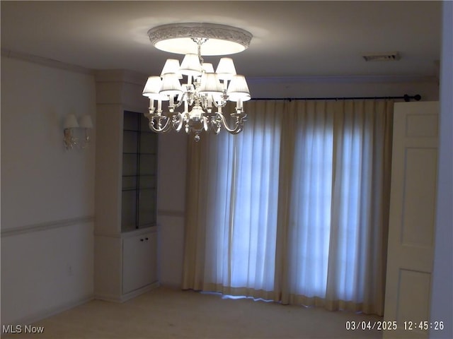 empty room with visible vents and a notable chandelier