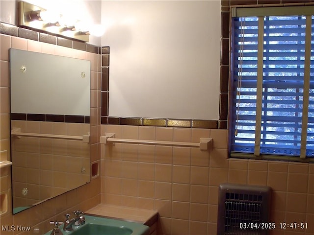 bathroom featuring a sink, tile walls, and heating unit