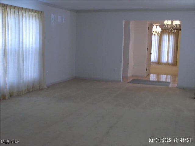 spare room featuring carpet floors and a notable chandelier