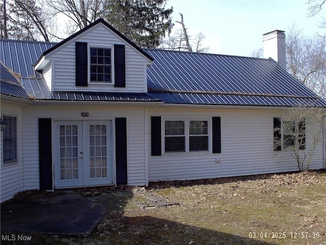 rear view of house with a chimney, metal roof, and french doors