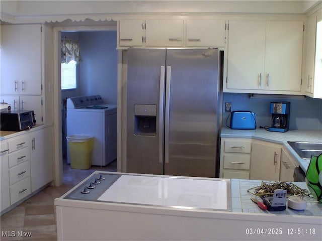 kitchen with washing machine and dryer, appliances with stainless steel finishes, white cabinets, and light countertops