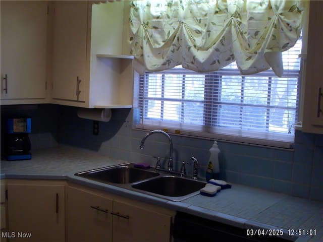 kitchen featuring tile countertops, open shelves, decorative backsplash, white cabinets, and a sink