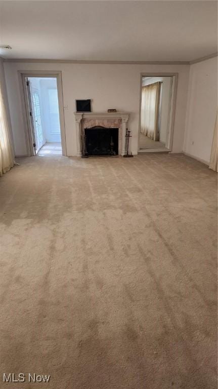 unfurnished living room with light carpet, a premium fireplace, visible vents, and crown molding