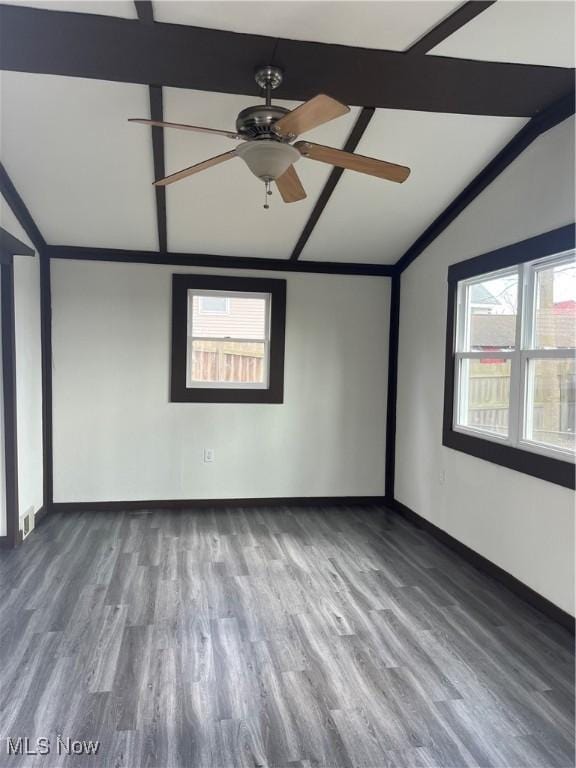 empty room featuring a ceiling fan, vaulted ceiling with beams, baseboards, and wood finished floors