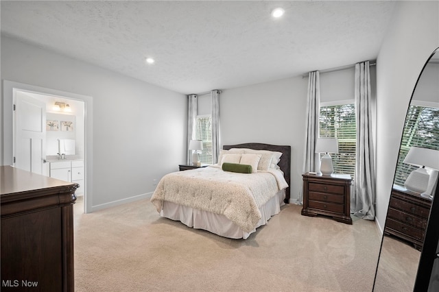 bedroom featuring light carpet, a sink, a textured ceiling, and baseboards