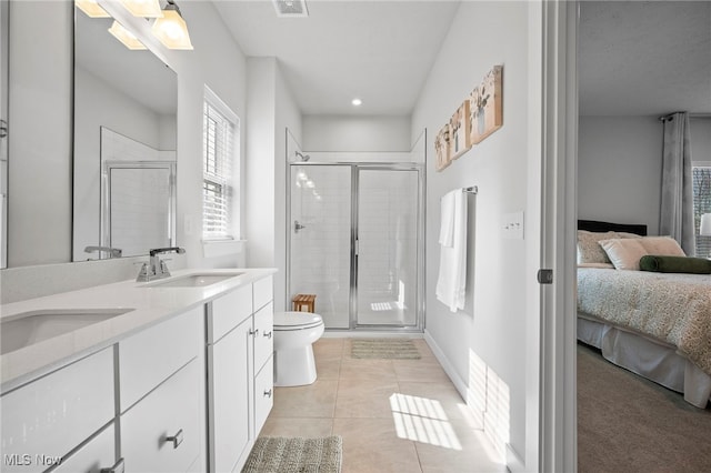 ensuite bathroom with connected bathroom, toilet, tile patterned floors, a shower stall, and a sink