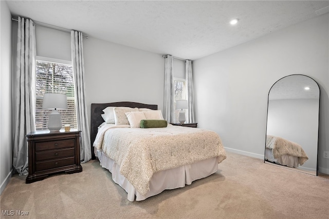 bedroom featuring a textured ceiling, carpet floors, multiple windows, and baseboards