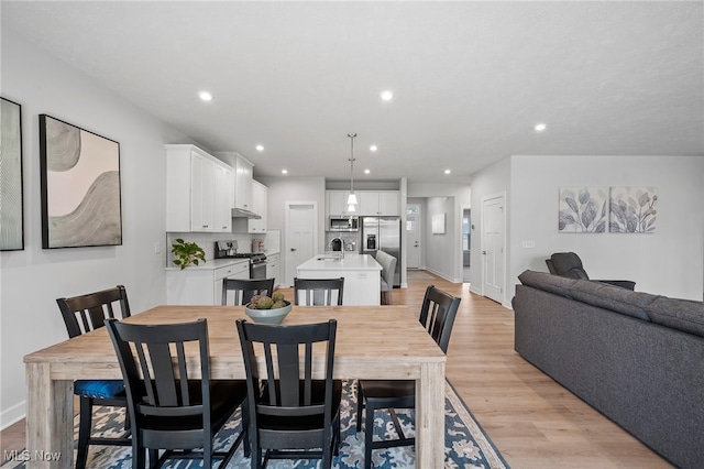 dining area with light wood-style floors, recessed lighting, and baseboards