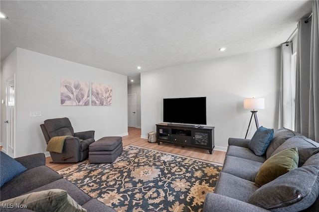 living room with recessed lighting, a textured ceiling, baseboards, and wood finished floors