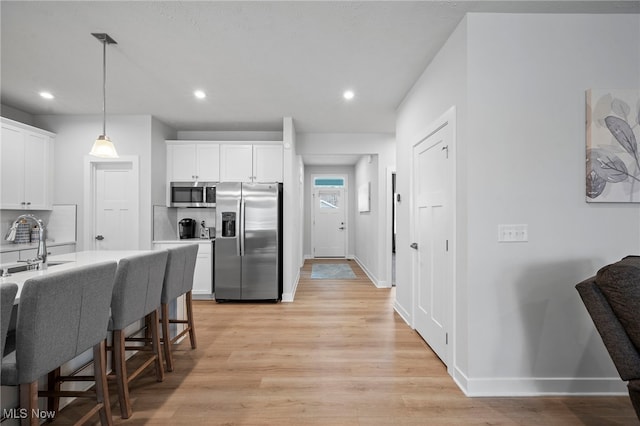 kitchen featuring stainless steel appliances, white cabinetry, backsplash, and light wood finished floors