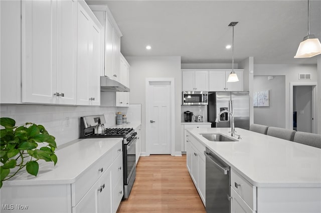 kitchen with under cabinet range hood, stainless steel appliances, a sink, visible vents, and light wood-type flooring