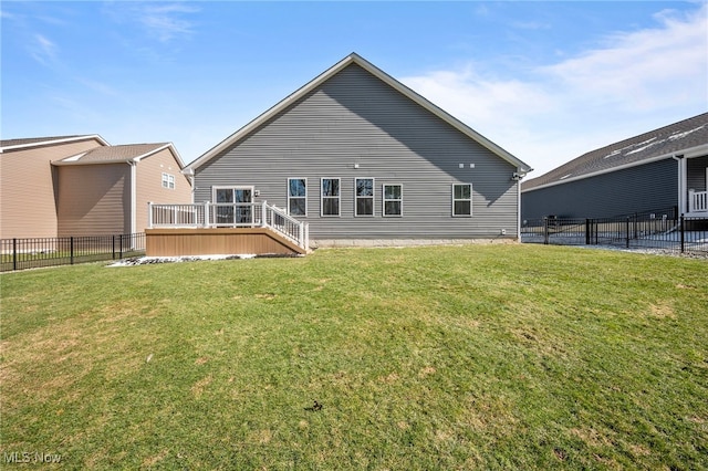 rear view of property featuring a lawn, fence, and a wooden deck