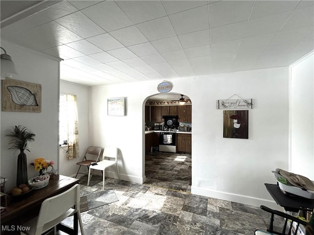 interior space with arched walkways, stone finish floor, and baseboards