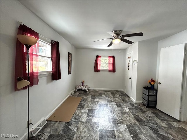 unfurnished room with ceiling fan and baseboards