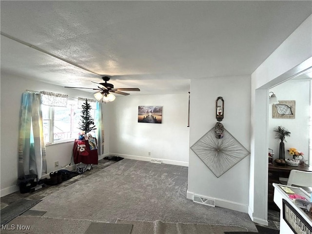 interior space featuring a ceiling fan, visible vents, a textured ceiling, and baseboards