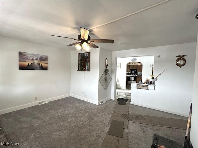 empty room with baseboards, dark carpet, visible vents, and a ceiling fan