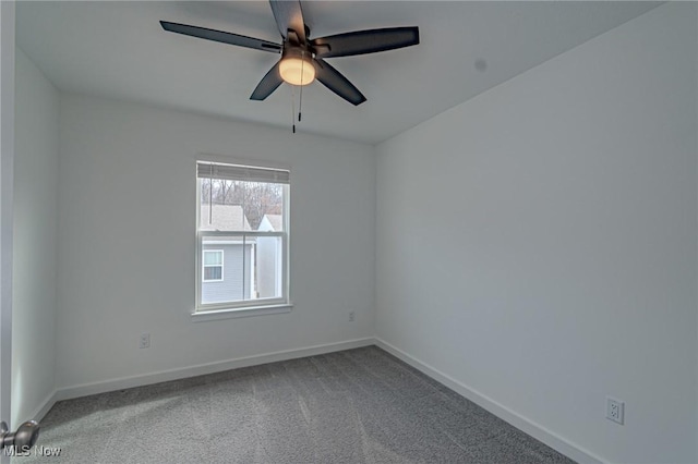 carpeted spare room featuring baseboards and a ceiling fan