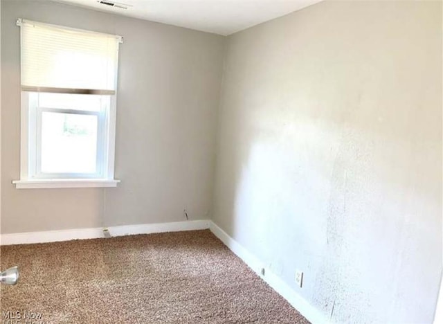 spare room featuring carpet floors, visible vents, and baseboards