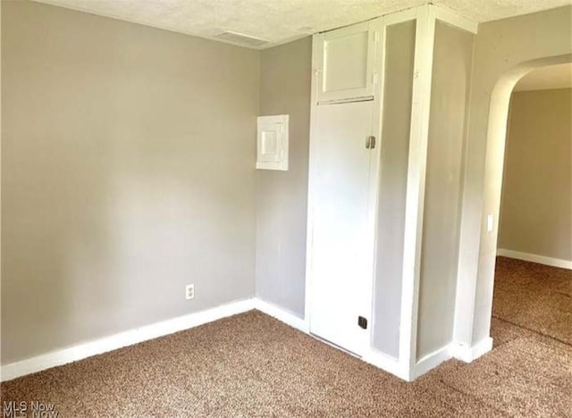 spare room featuring carpet floors, baseboards, arched walkways, and a textured ceiling