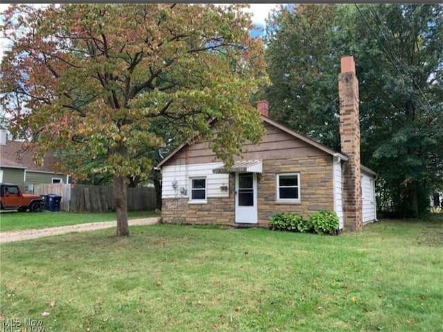 view of front facade featuring a chimney, a front yard, and fence