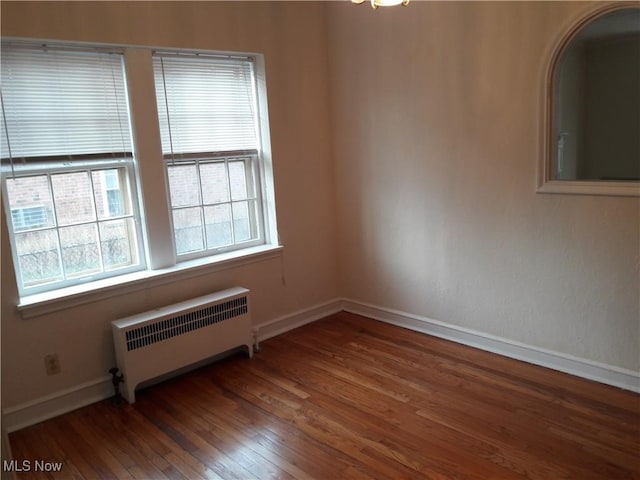 spare room with radiator, hardwood / wood-style flooring, and baseboards