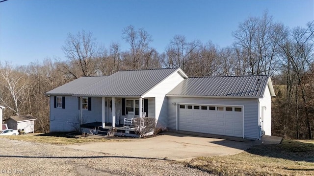 ranch-style home featuring metal roof, concrete driveway, a porch, and a garage