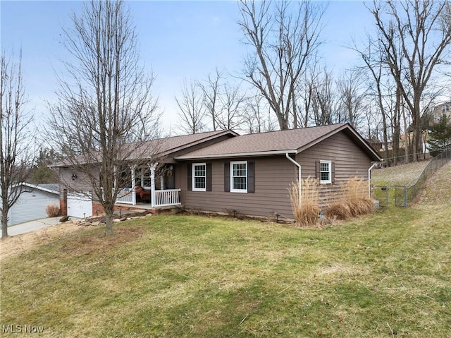 ranch-style house featuring a shingled roof, a front yard, covered porch, and driveway