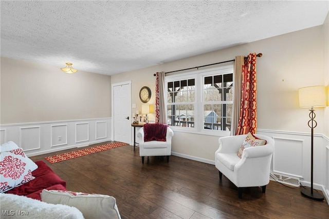 sitting room with a textured ceiling, wainscoting, and wood finished floors