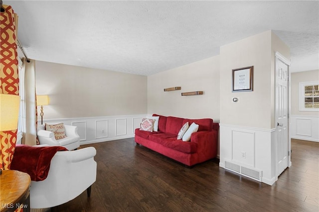 living area featuring wainscoting, visible vents, a textured ceiling, and wood finished floors