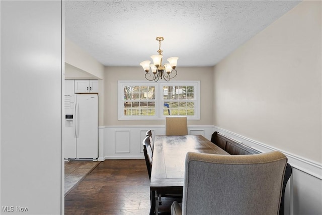 dining room featuring a wainscoted wall, a textured ceiling, and an inviting chandelier